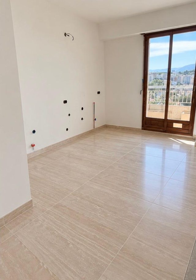 Cuisine après les travaux : sol en grands carreaux beige aspect travertin et plinthes assorties