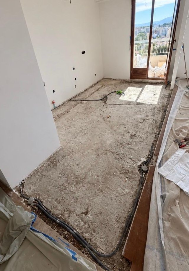 Cuisine avant les travaux : sol mis à nu jusqu'à la chape, gaines visibles