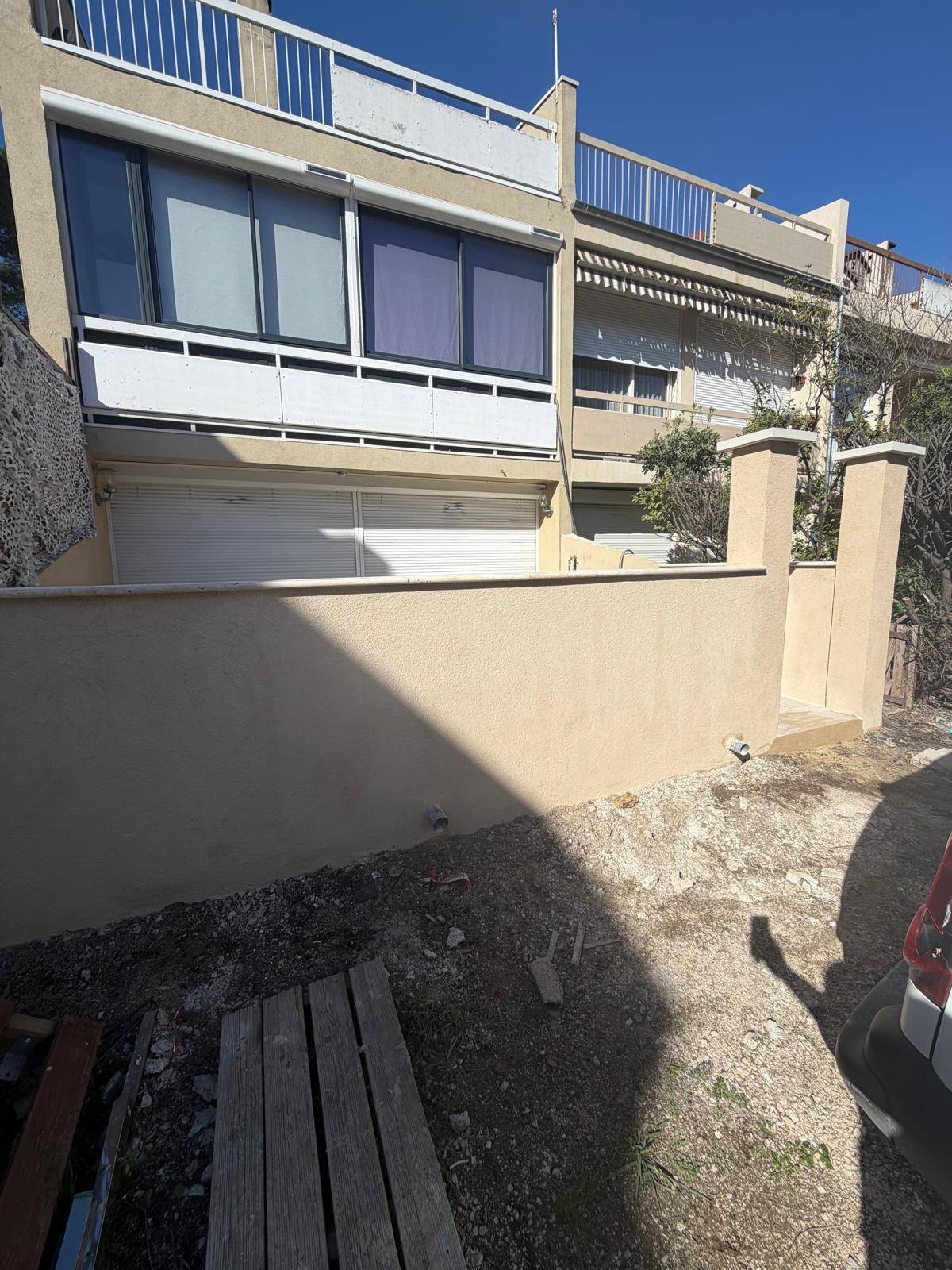 Muret de clôture et piliers enduits devant une résidence
