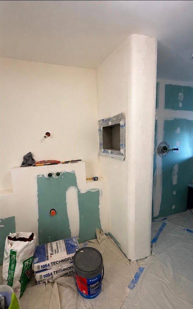 Salle de bain avant les travaux : muret et niche bruts, sacs de colle sur le chantier