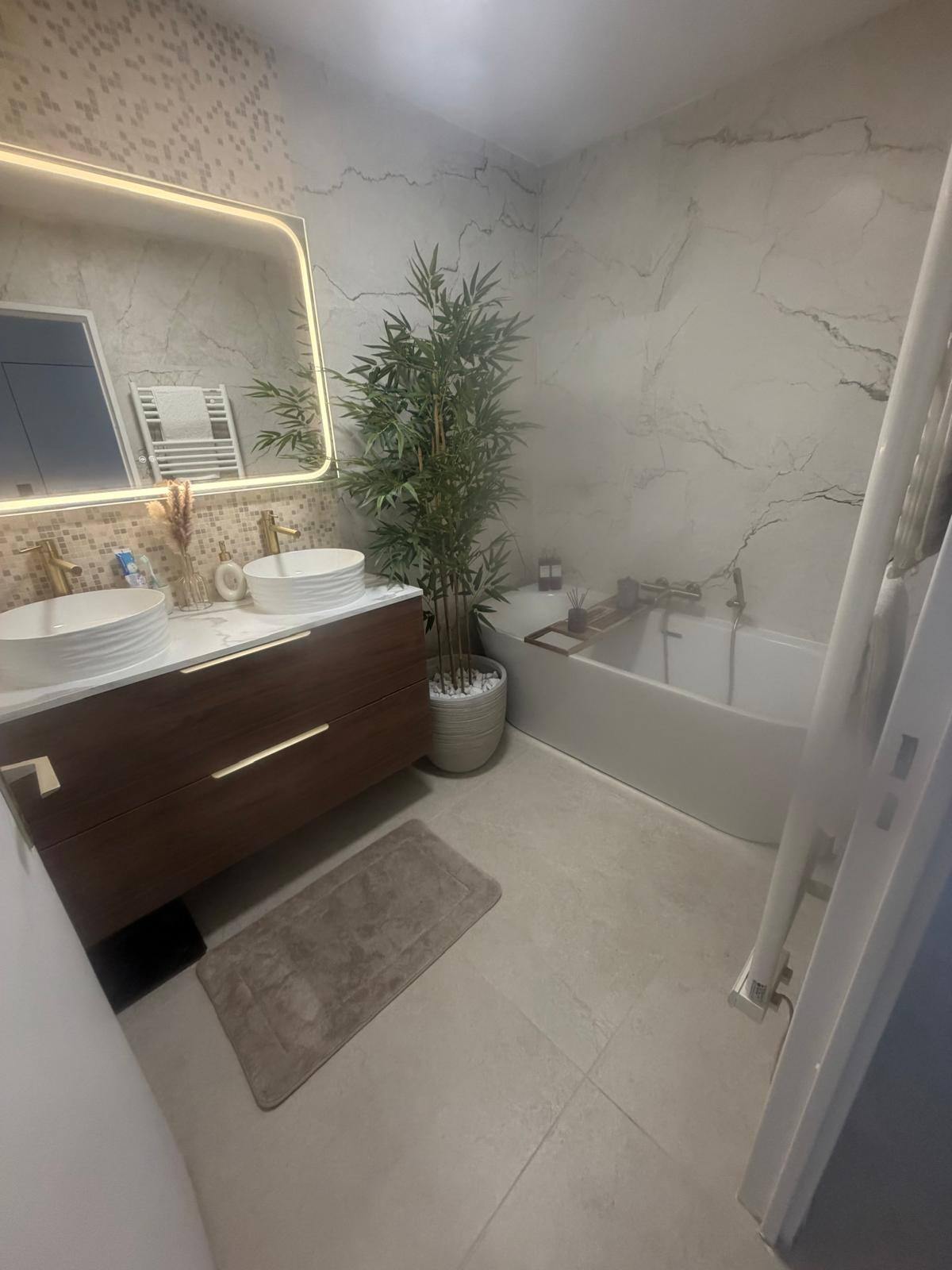 Salle de bain avec carrelage mural aspect marbre blanc, double vasque et baignoire