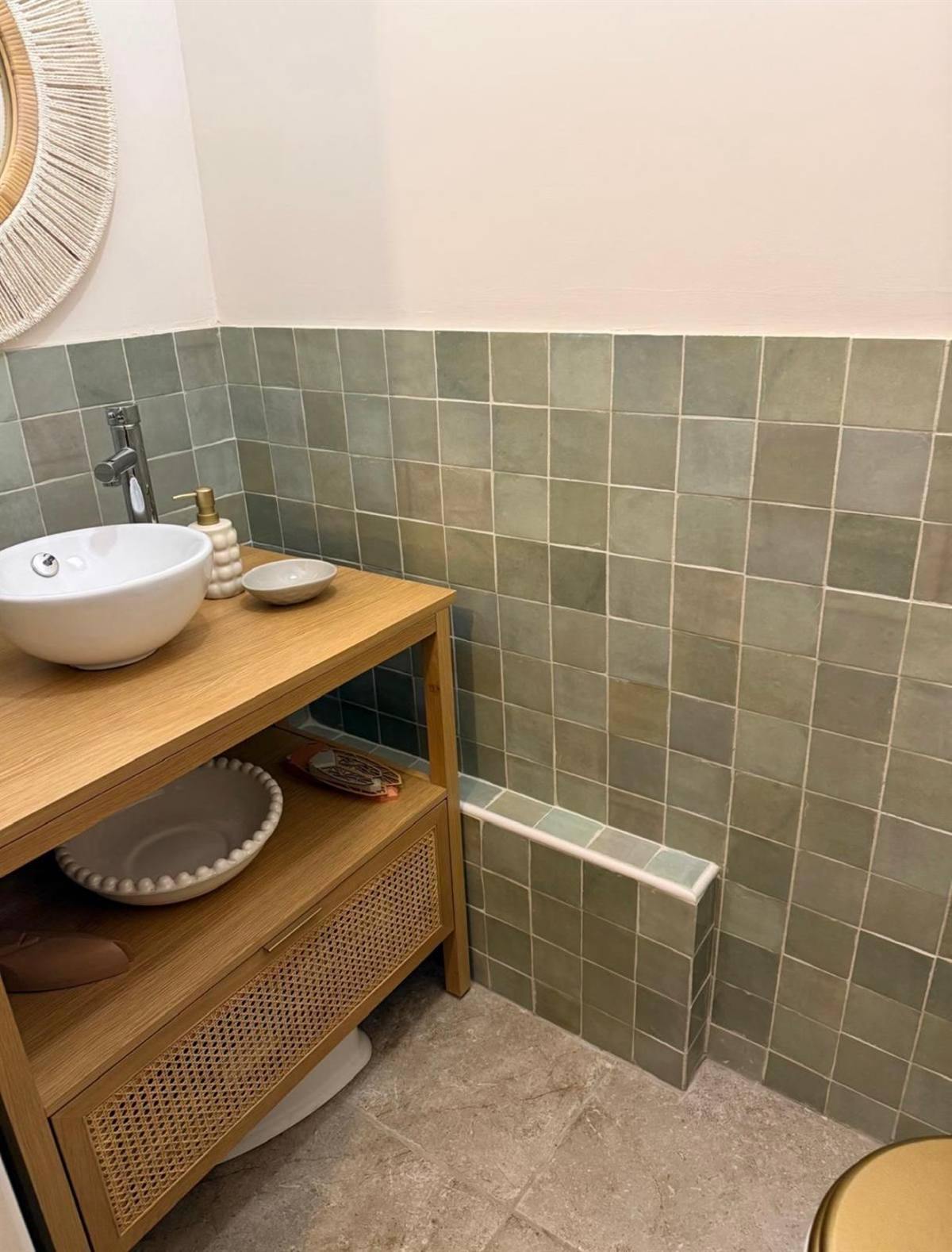 Meuble vasque en bois devant un mur de carreaux verts posés à mi-hauteur
