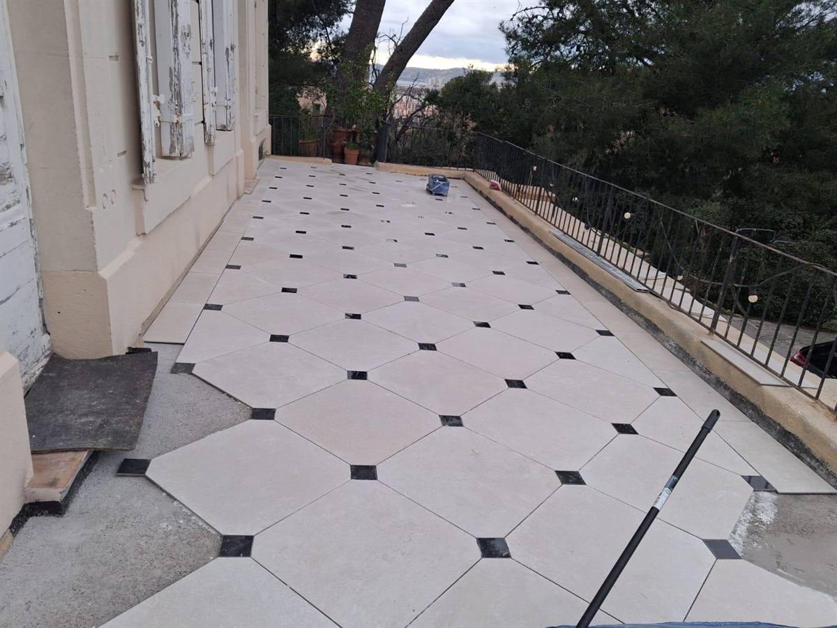 Dalles octogonales claires et cabochons noirs le long d'une façade