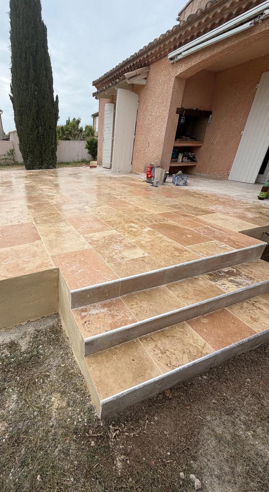 Terrasse surélevée en travertin avec trois marches devant une maison provençale