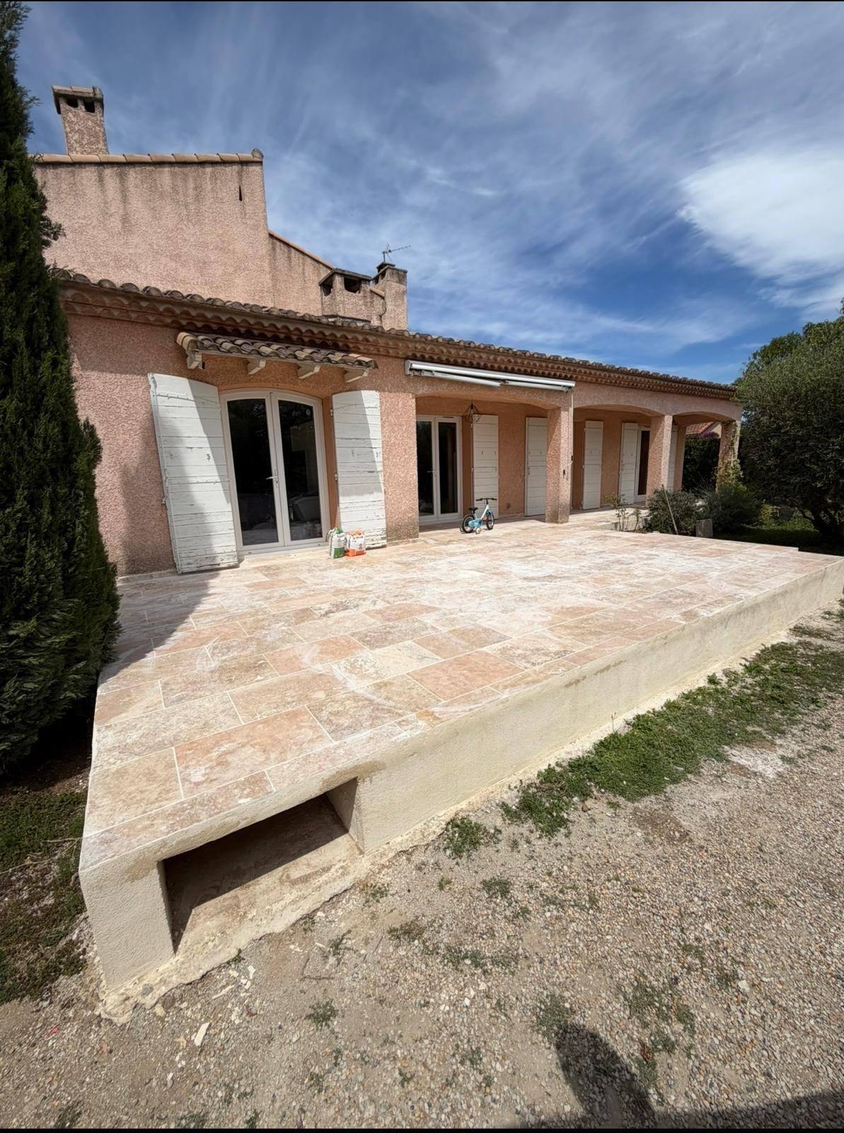 Terrasse en travertin terminée devant la façade d'une villa